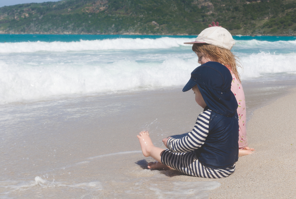 young kids wearing sun protective clothing at beach