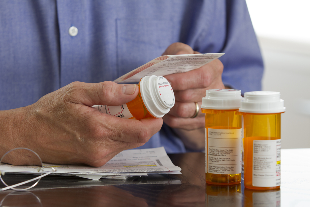 hand holding prescription bottles and checking their labels