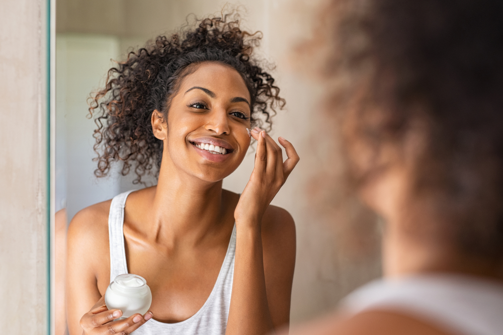 woman applying moisturizer to face